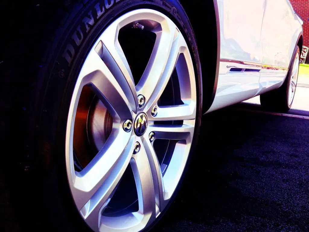 A white car sporting a Dunlop tyre with shiny rims on a parking lot